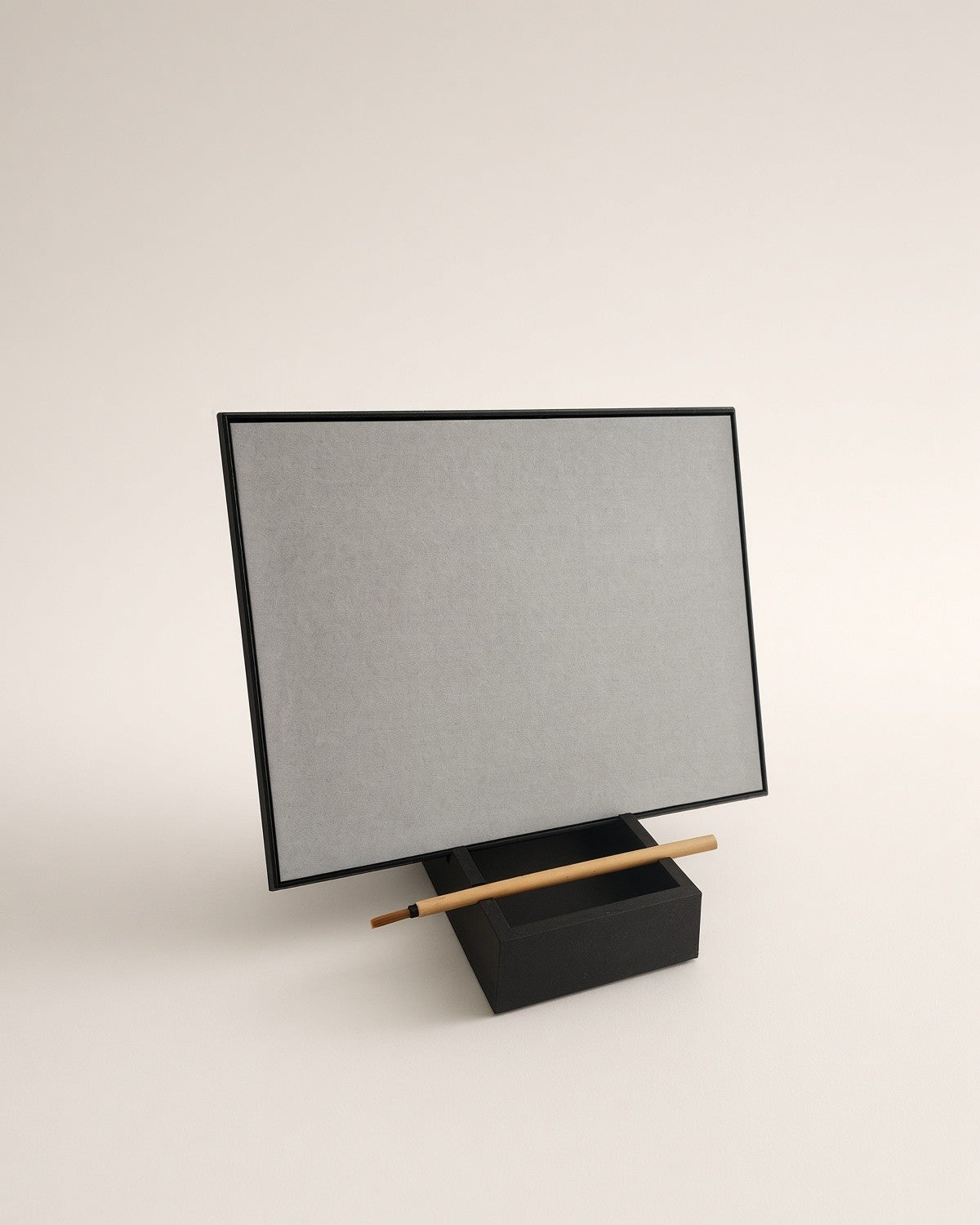 The board in landscape from an angle, resting in its stand with the brush across the water well