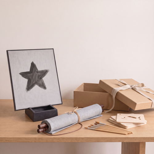 The Water Painting Gift Set on an oak table: the Water Easel with a water-painted star, the Water Canvas rolled on its wooden rods, brushes, wooden stencils and a kraft gift box
