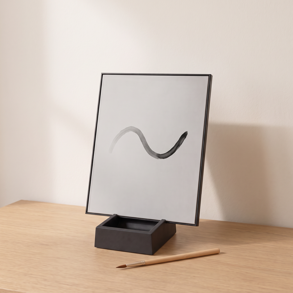 The Little Otter Water Easel standing on an oak table with a simple wave painted in water, fading at one end, and a bamboo brush in front