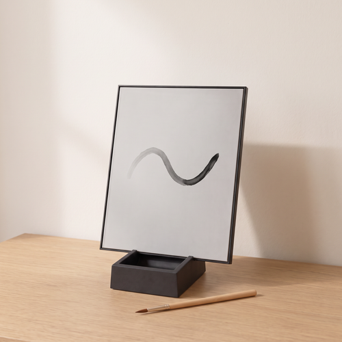 The Little Otter Water Easel standing on an oak table with a simple wave painted in water, fading at one end, and a bamboo brush in front